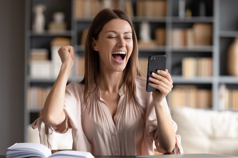 žena se veseli loto rezultatima na mobitelu