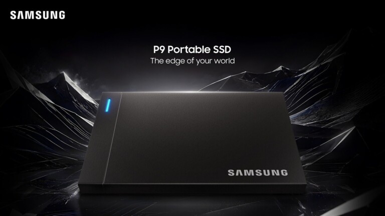 Samsung P9 Portable SSD, a dark gray rectangular external drive with a blue LED indicator strip, on a reflective black surface against a background of jagged dark crystal formations.